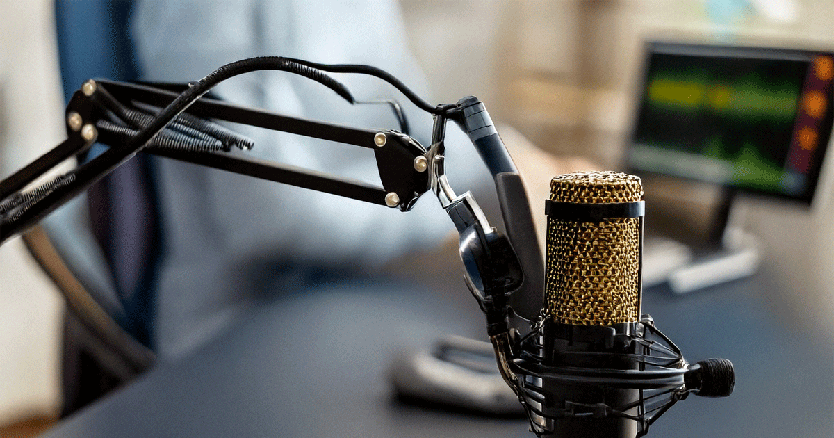 A microphone hangs from a retractable arm in a podcast recording studio.