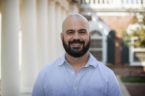 Headshot of Ernesto Benitez in blue shirt standing outside in front of white columns.