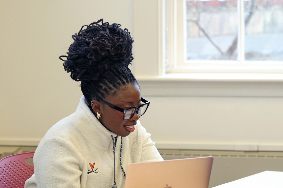 A woman sitting at a table studying on her laptop.