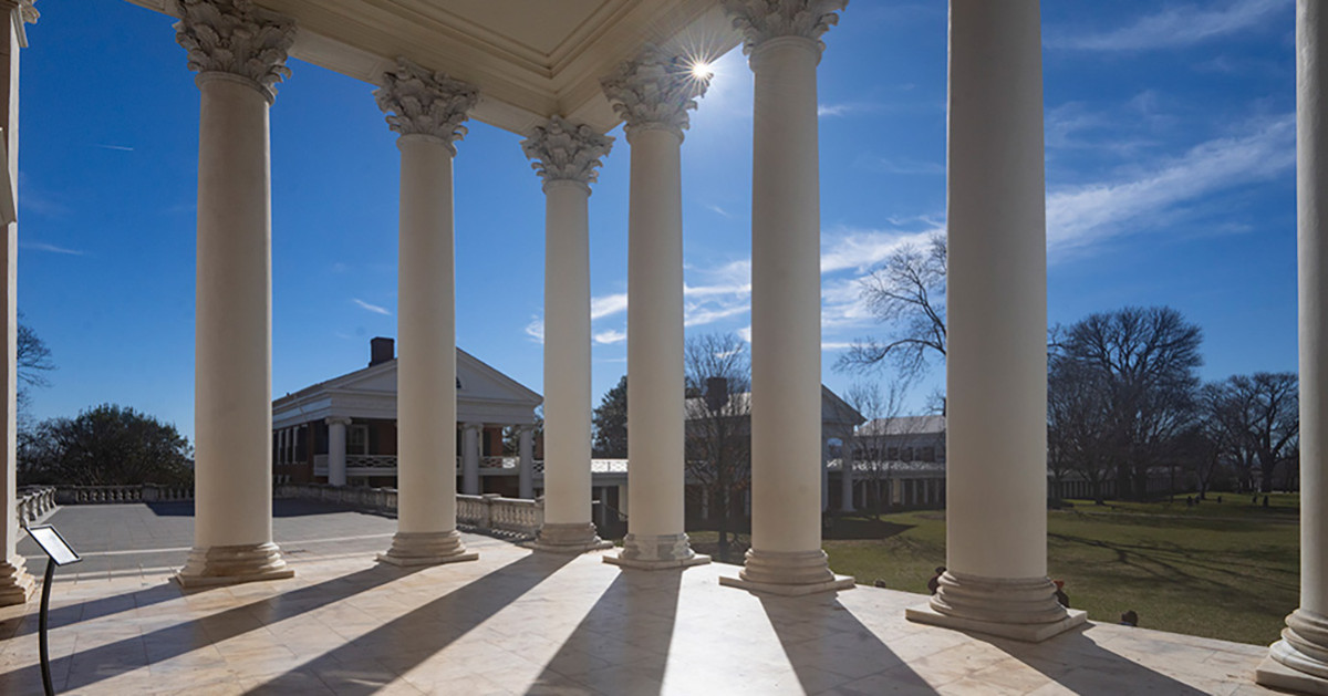 View from the rear of the Rotunda looking through pillars as the sun shines in a blue sky.