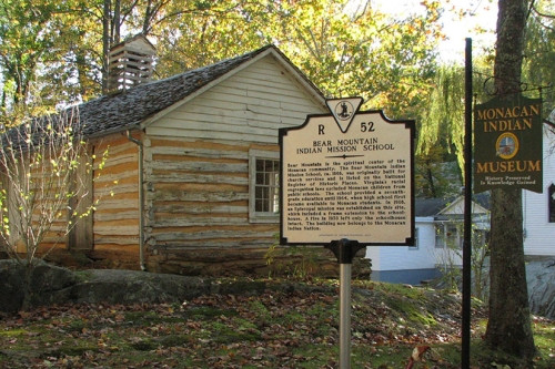 The historic Bear Mountain Indian Mission school log cabin with memorial marker in foreground.