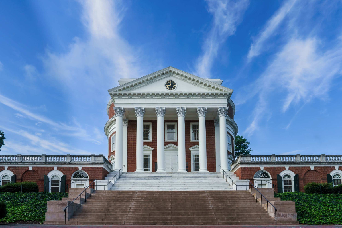 The columned front facade of the UVA Rotunda with bright blue sky in background.