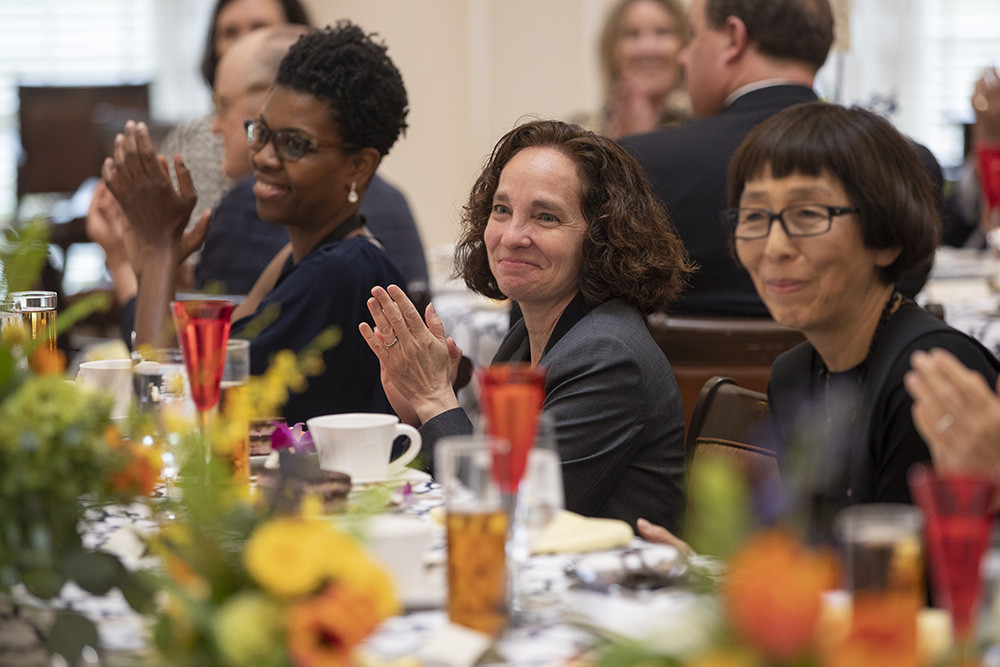 A diverse group of women clapping while sitting at a decorated dinner table