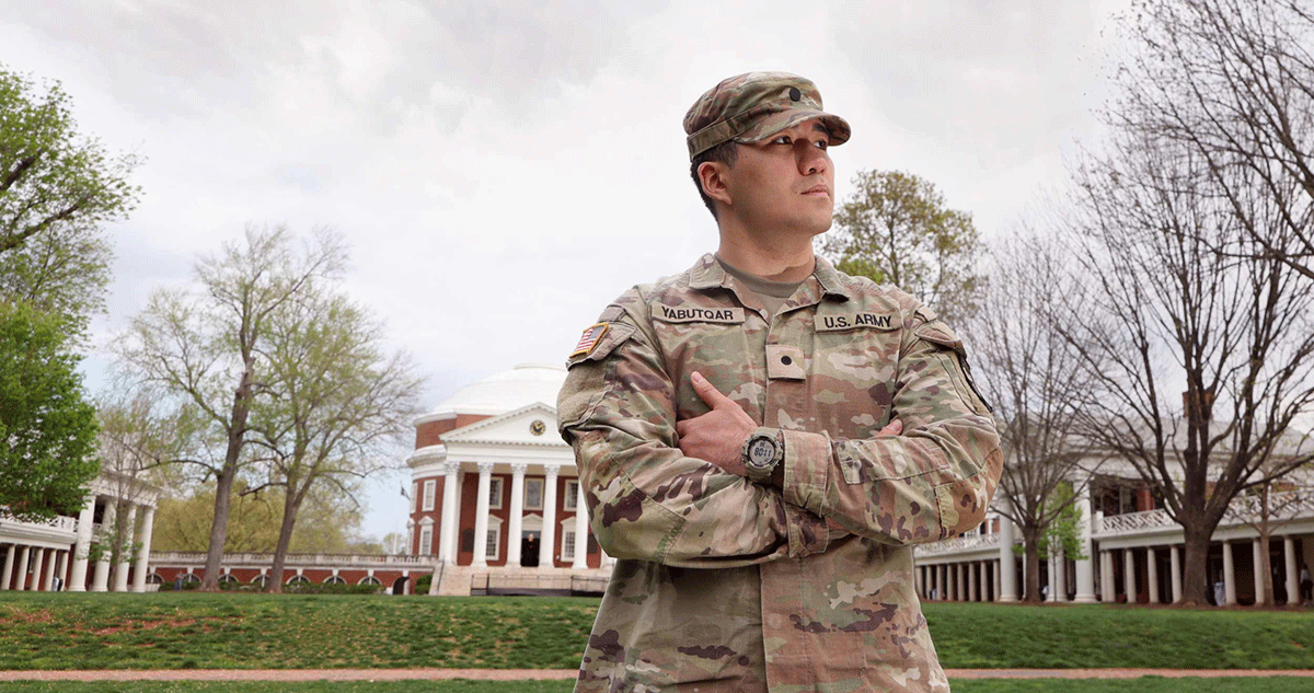 Army Cadet Azamat Yabutqar poses with arms crossed on the Lawn with the Rotunda in the background.