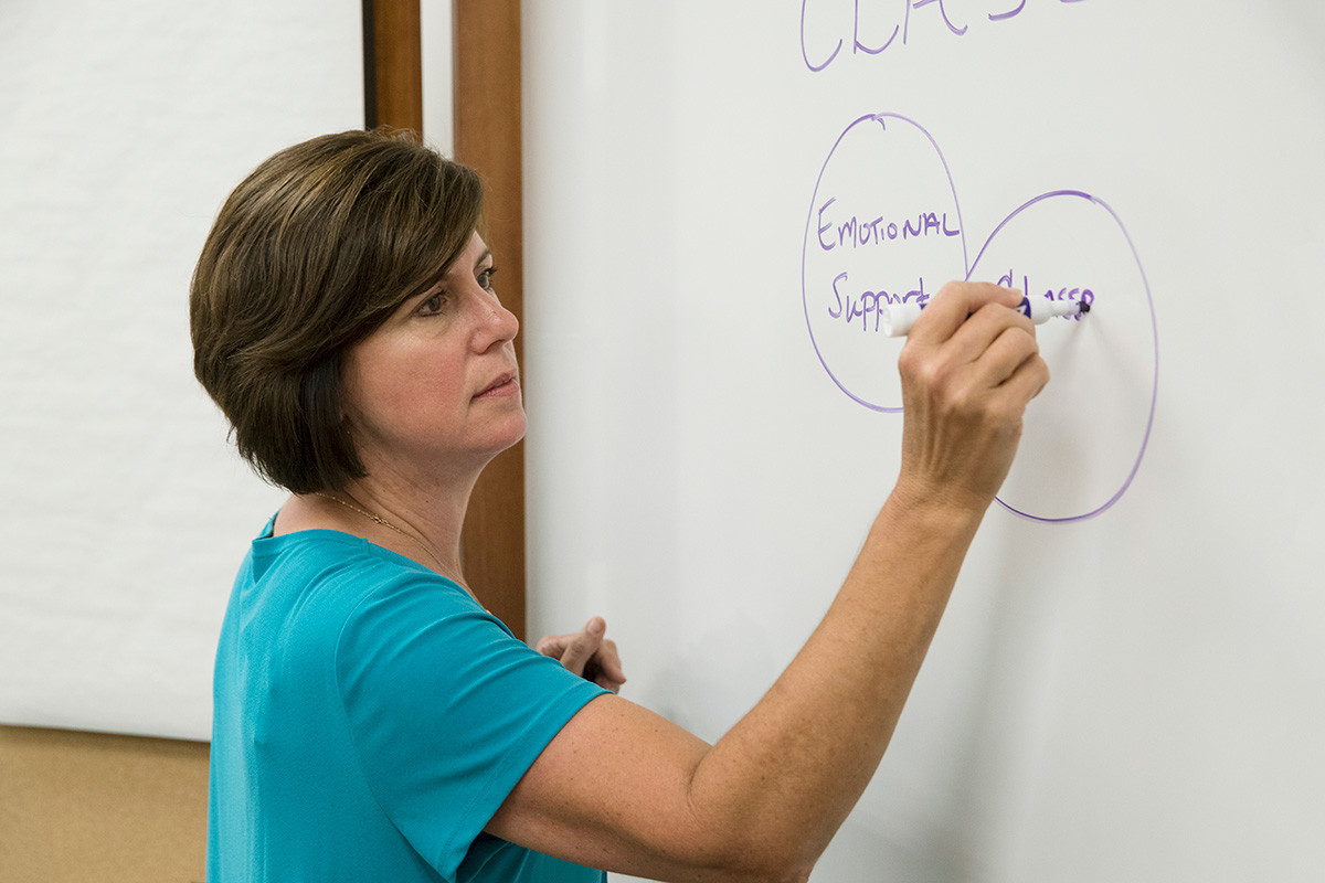 Female professor writing on a whiteboard.