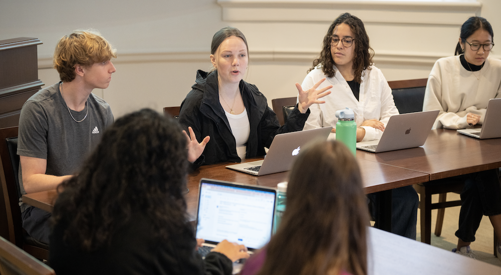 Six UVA students in a study area, sitting at tables with their computers.