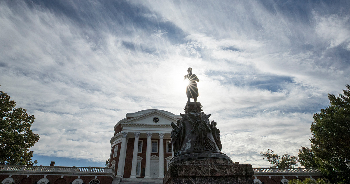 Upward view of the Thomas Jefferson statue in front of UVA's Rotunda with a sunburst appearing through the statue's arm.