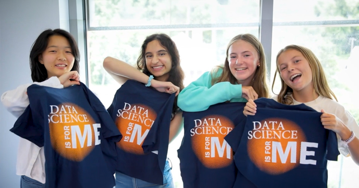 Four high school students holding up T-shirts that say 