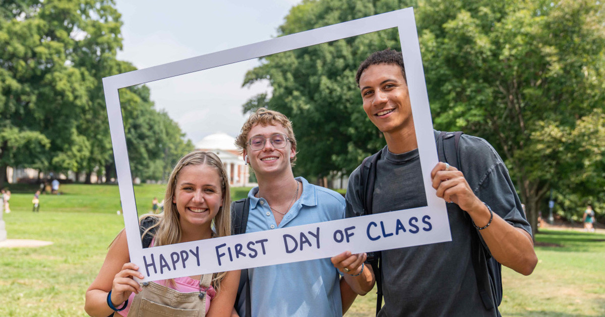 Three students on the Lawn pose inside Polaroid frame prop that says 