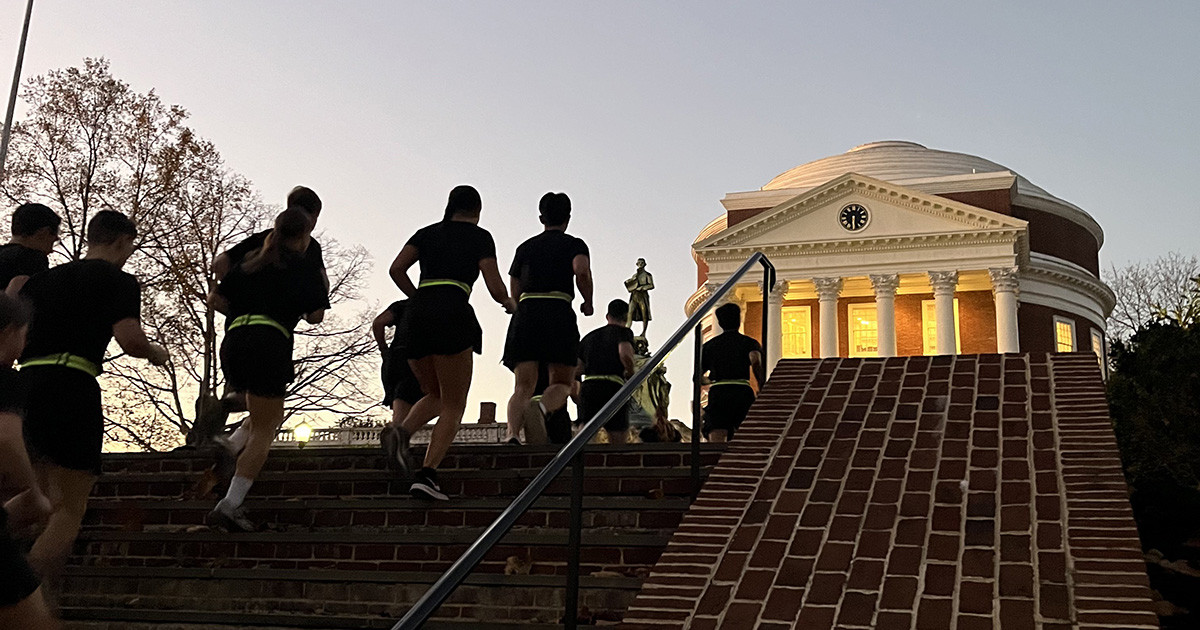 Army cadets running up the stairs toward UVA's Rotunda at sunrise.