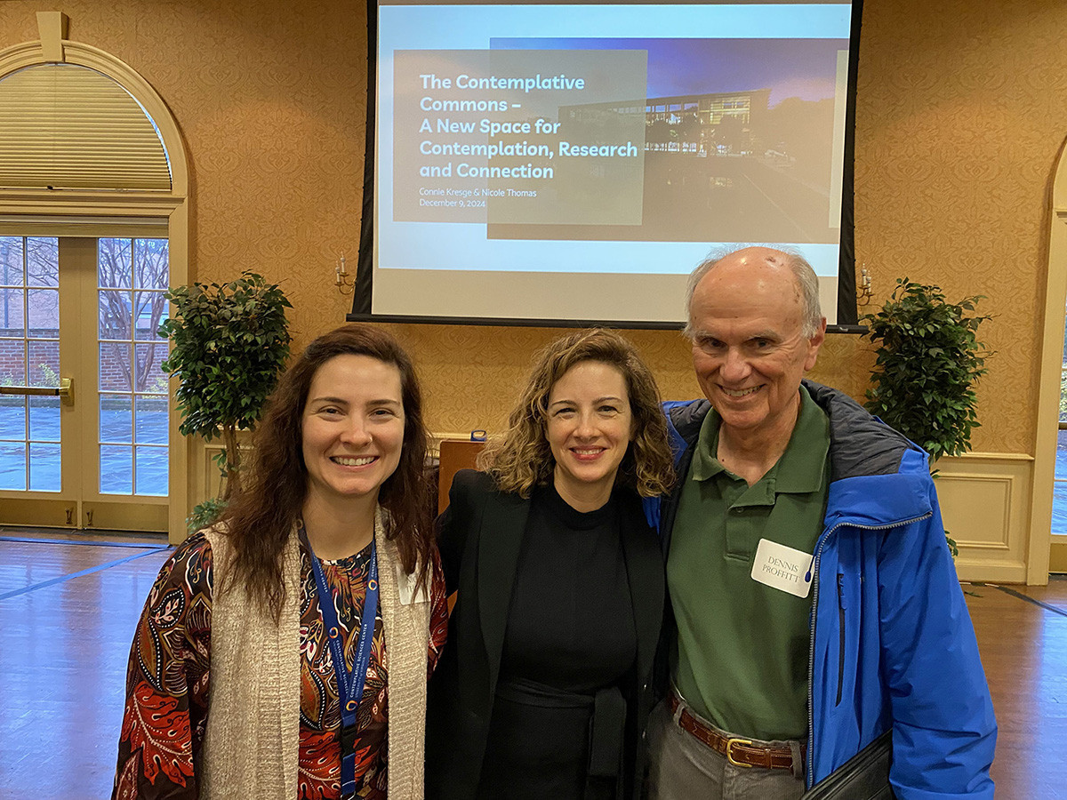 Three people are standing together in front of a projector screen. 