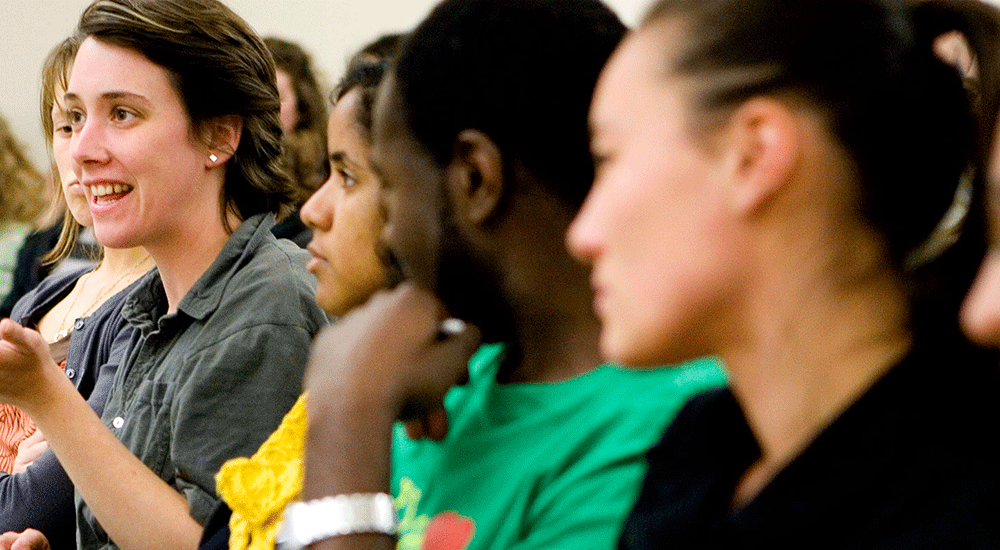 Three students looking towards classmate making comment in class.