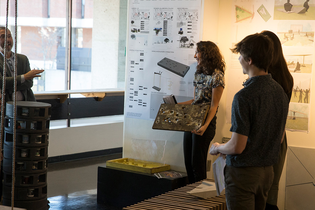 Three students standing in front of a poster board.