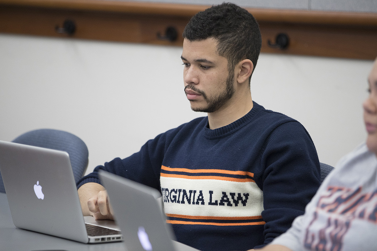 Male student wearing a Virginia Law t-shirt sitting in front of a laptop.