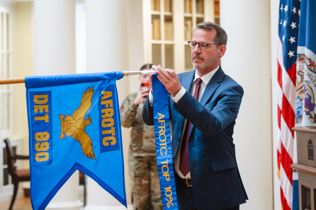 Provost Ian Baucom attaches an AFROTC banner to a flag pole.