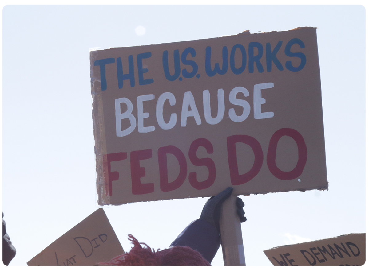 An upraised arm holding a hand-lettered sign with the words 